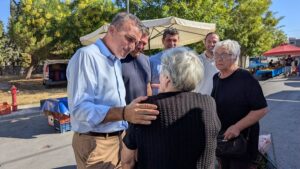 Ο Θ.Μαμάκος συνομιλεί με ηλικιωμένη κυρία σε δρόμο λαικής αγοράς.