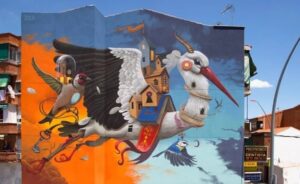 Mural on a high building wall depicting a stork and two little birds flying