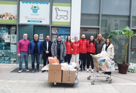 Εκπρόσωποι της ΕΑΛ και του Κοινωνικού Παντοπωλείου μπροστά από τις κούτες της προσφοράς τροφίμων